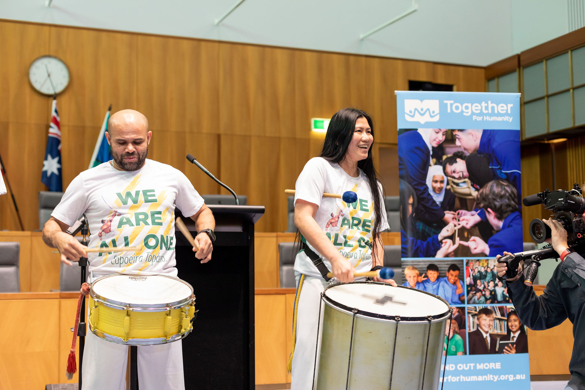 Image of 2 people dressed in white t-shirts playing musical instruments.