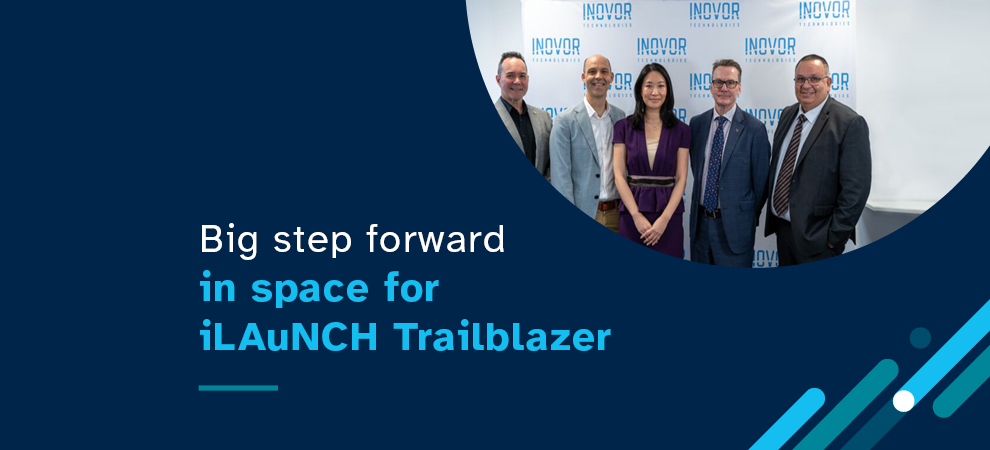 Image of 5 people standing in front of a banner and a white wall with the text 'Big step forward in space for iLAuNCH Trailblazer