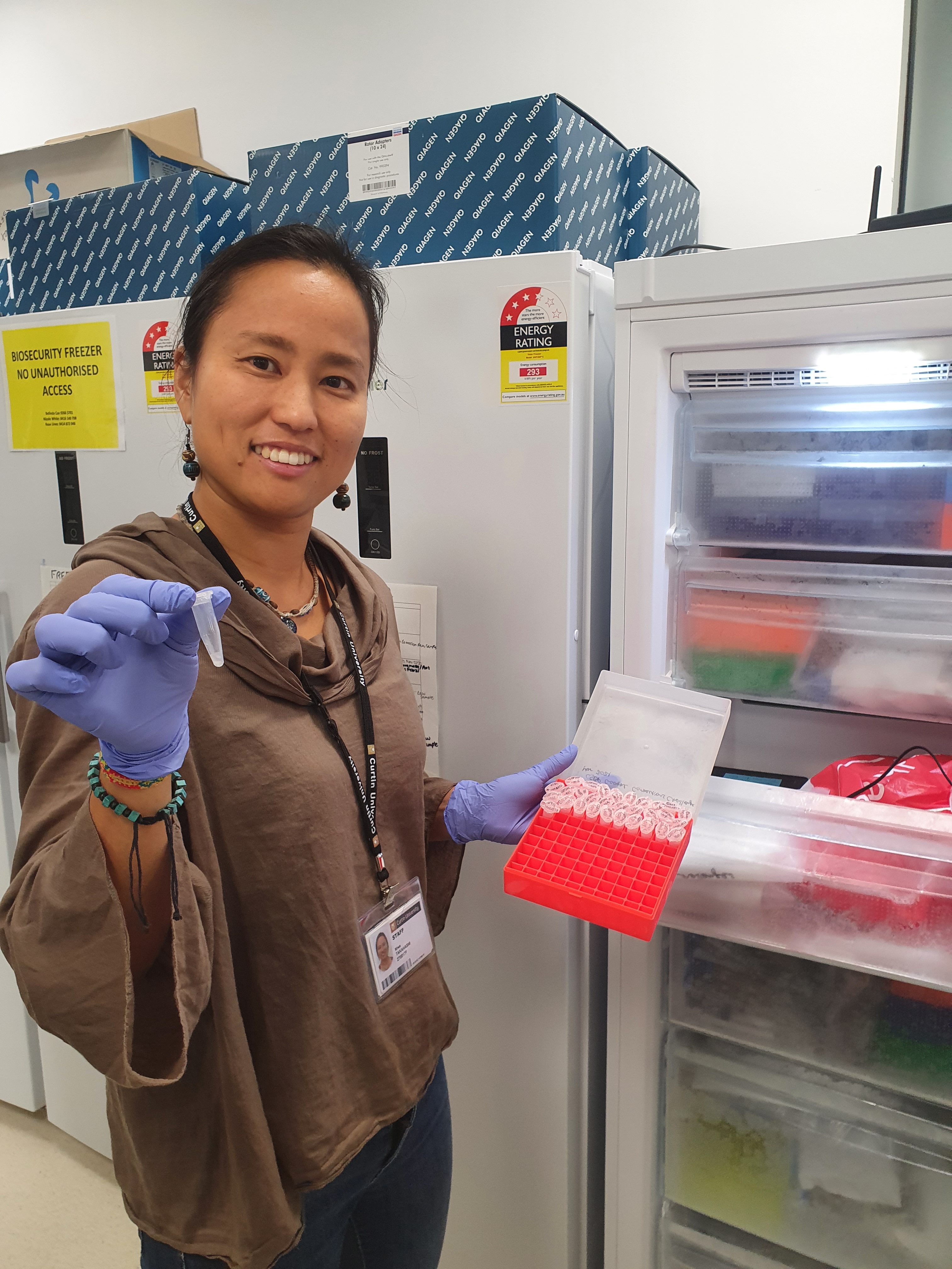 Miwa Takahashi smiling and holding a sample in front of an open fridge.