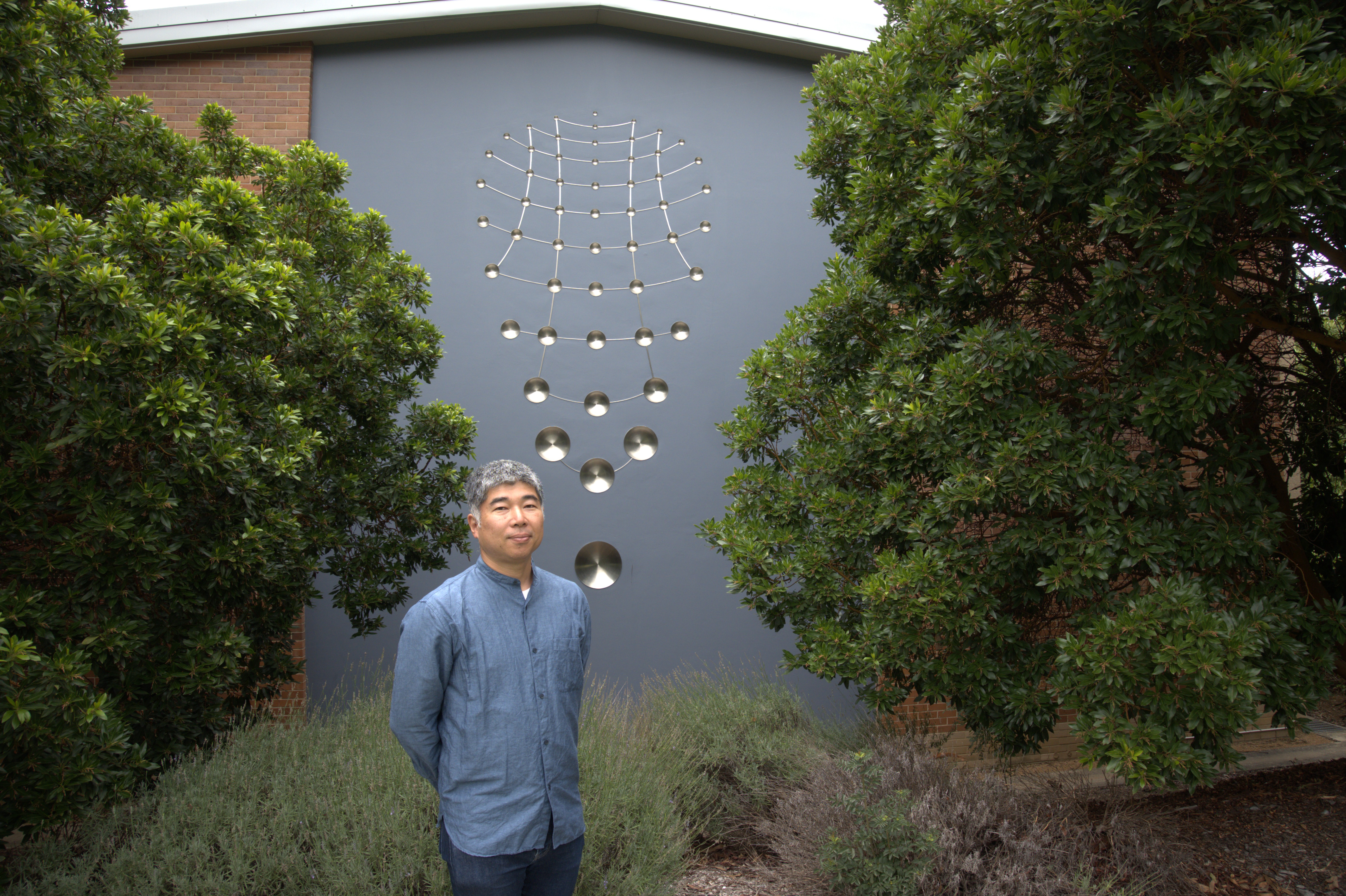 man standing outside in front of a grey building.