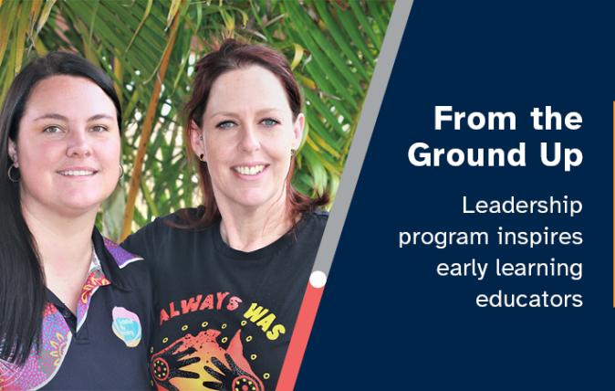 Two child care workers smiling and wearing colourful indigenous Australian t-shirts, with green, leafy plants in the background.
