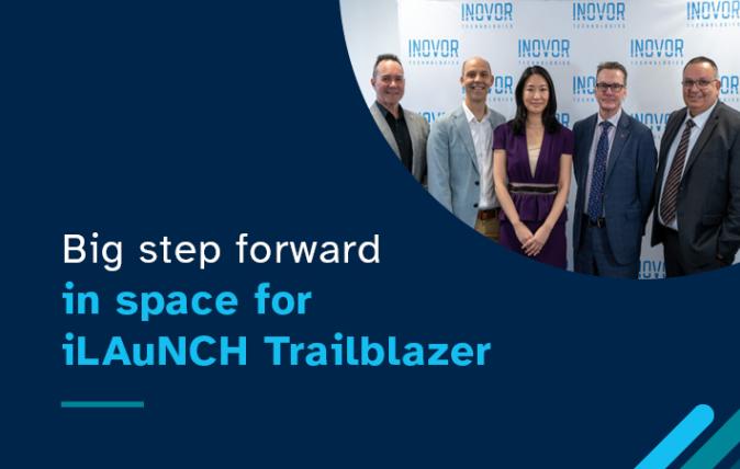 Image of 5 people standing in front of a banner and a white wall with the text 'Big step forward in space for iLAuNCH Trailblazer