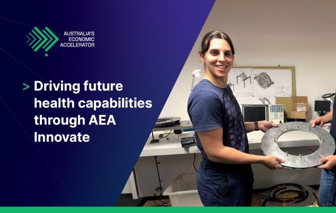 Two people holding a metal disk in an engineering lab smiling.